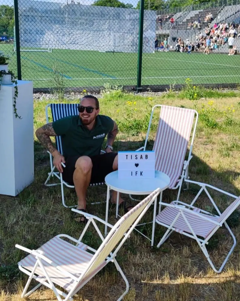 Christoffer vid fotbollsplanen med skylten TISAB hjärta IFK